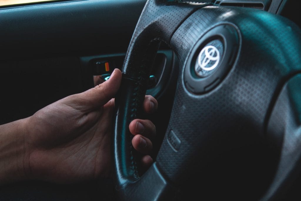 driver's hand on Toyota steering wheel