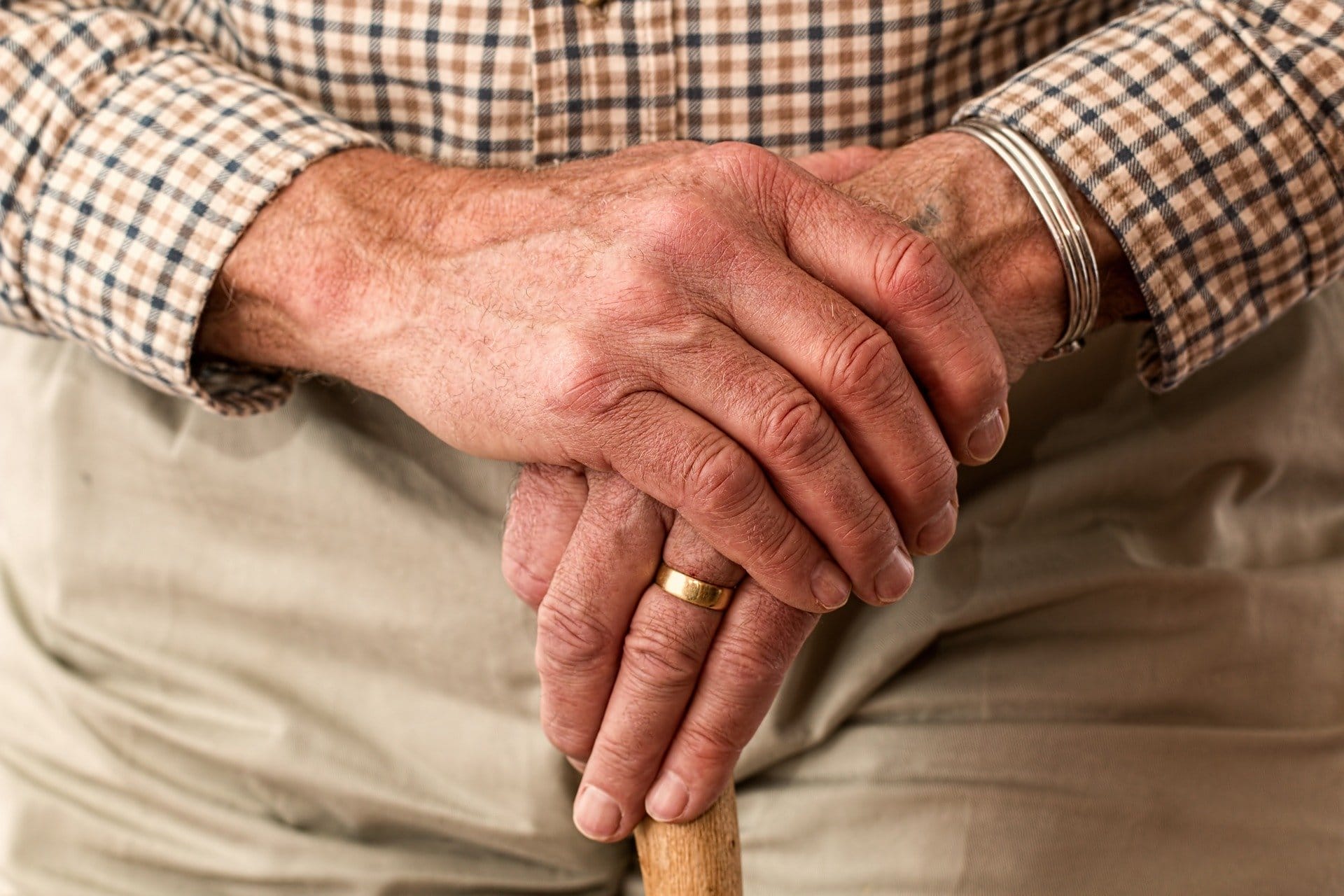 parkinson's patient with hands on cane